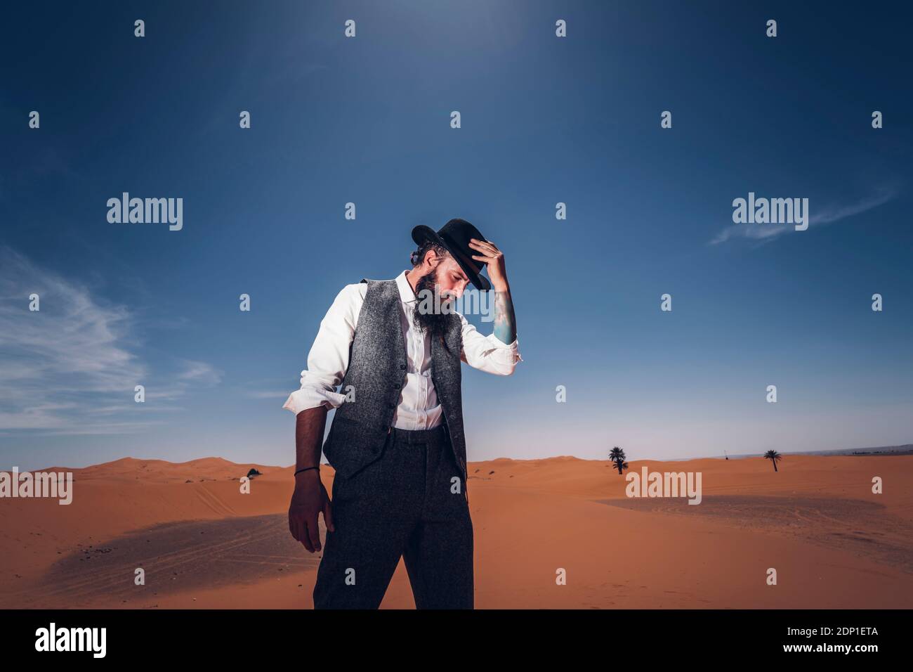 Mann mit Bart und Hut in den Dünen der Wüste von Marokko Stockfoto