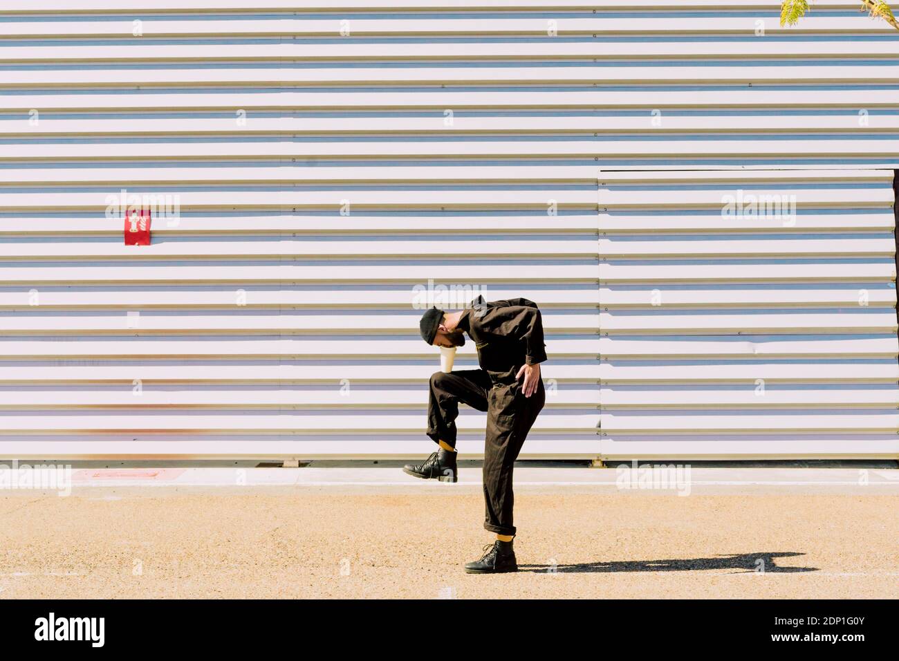 Mann trägt schwarz Gesamt Balancing mit vor der Industrie Gebäude Stockfoto