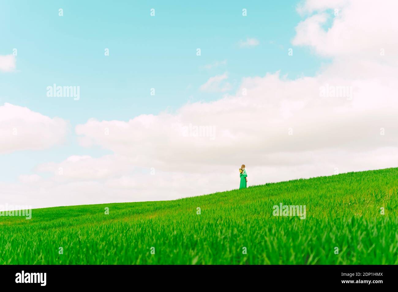 Rückansicht der Frau trägt grünes Kleid auf einem stehen Feld mit Blick auf die Entfernung Stockfoto