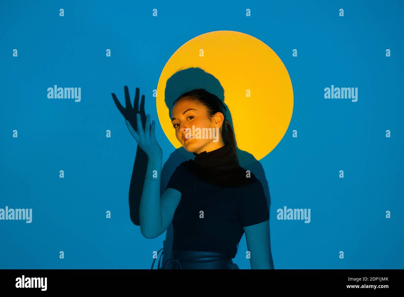 Junge Frau, die sich in blauem Licht vor Gelb bewegt Kreis Stockfoto