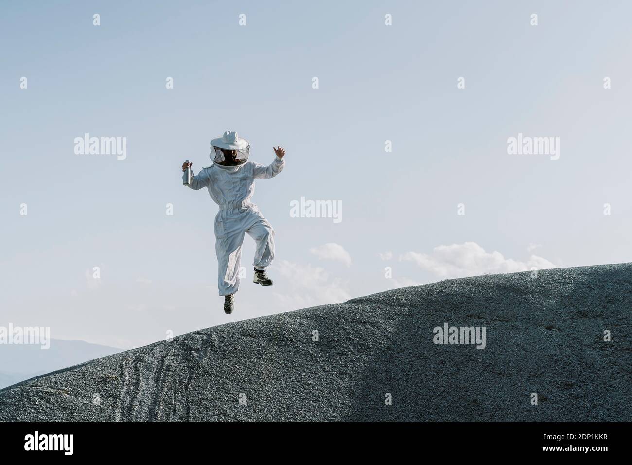 Mann in einem Imkerkleid, der auf einem Hügel springt Stockfoto