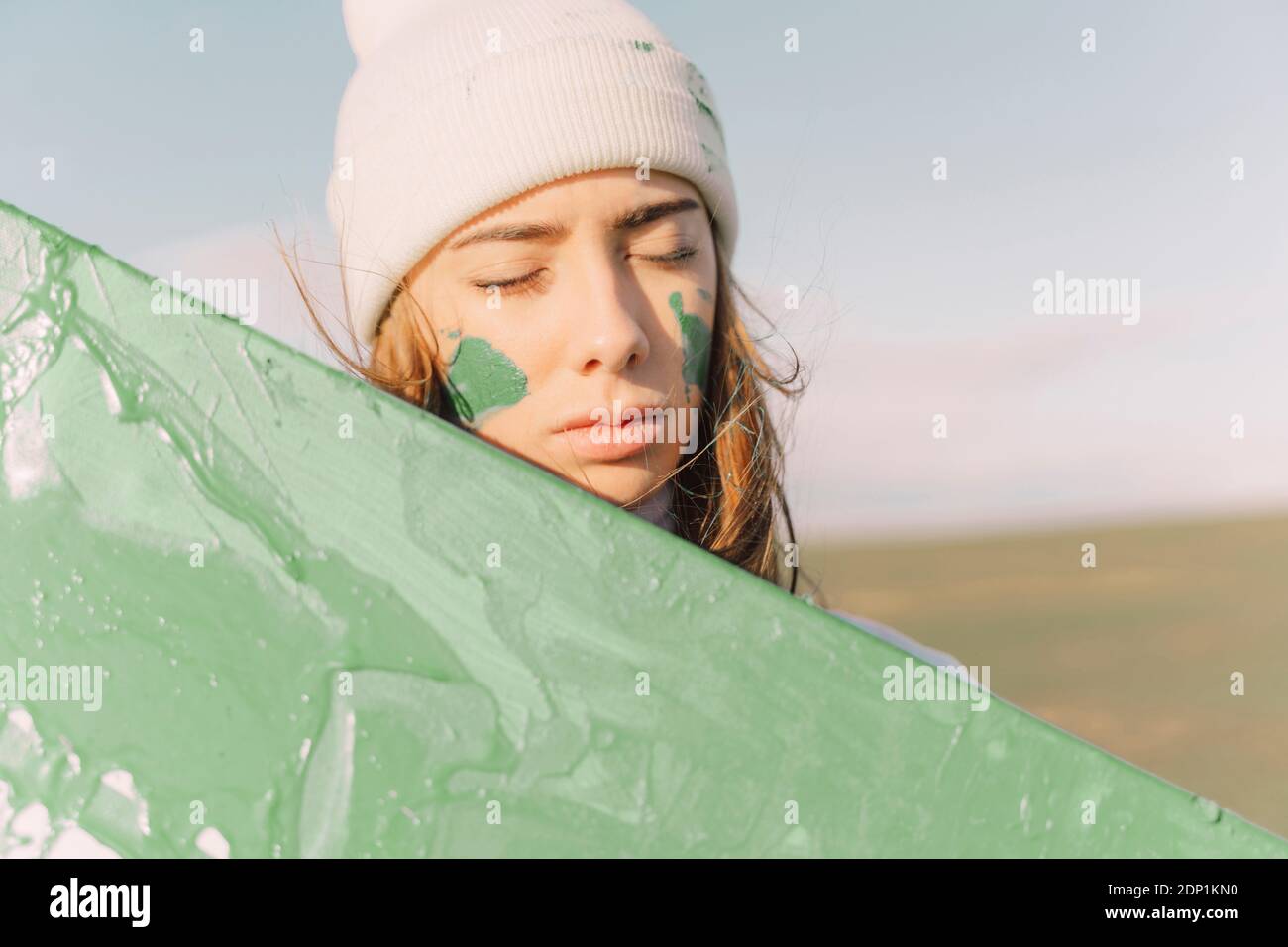 Junge Frau mit Facepaint, die über grüne Leinwand blickt Stockfoto