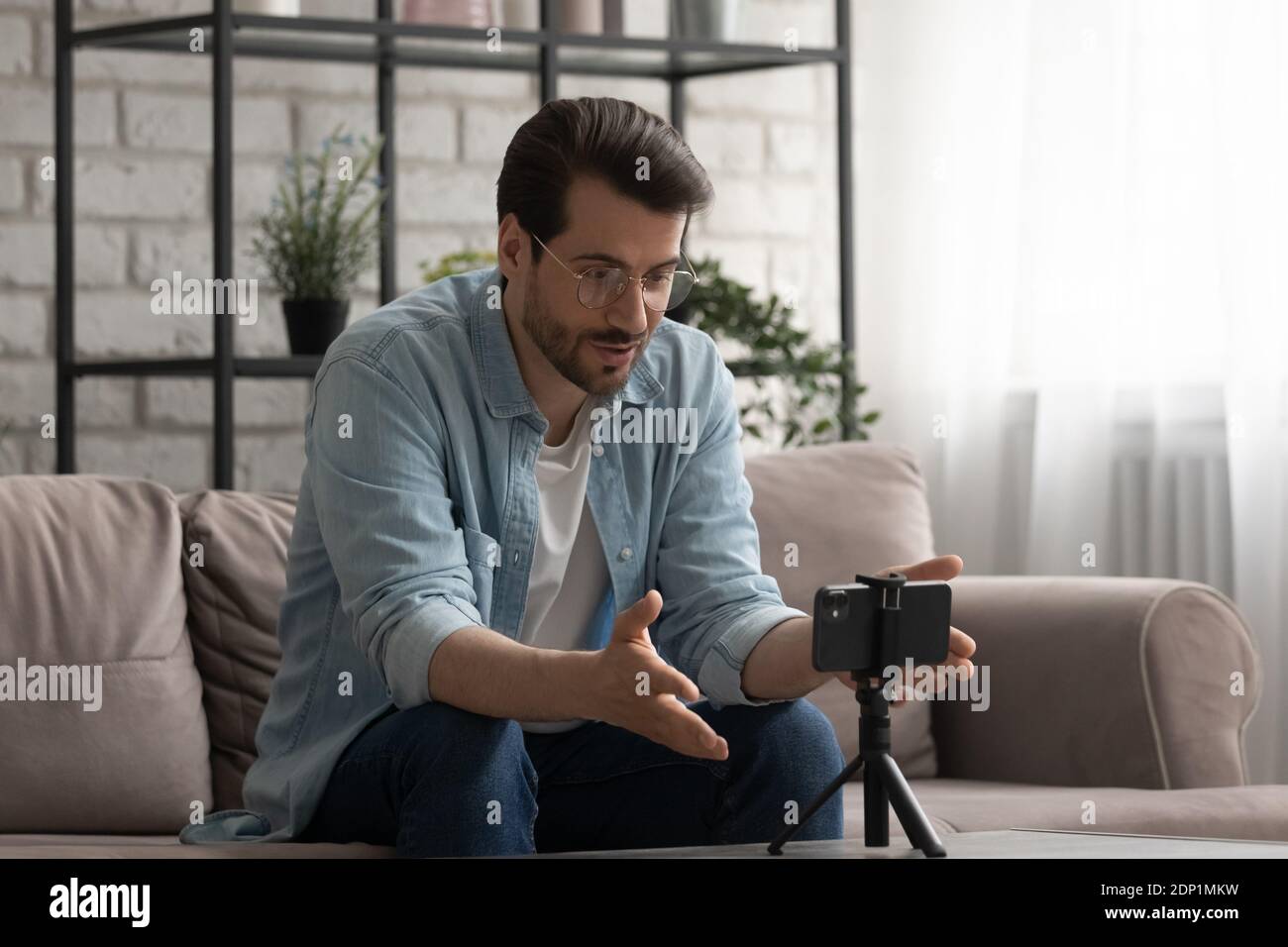 Junger Mann macht Videocall von Zelle an Halter fixiert Stockfoto