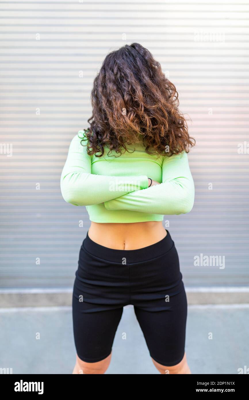 Junge Frau trägt grüne Crop Top mit Haaren vorne Von Gesicht posiert gegen graue Wand Stockfoto