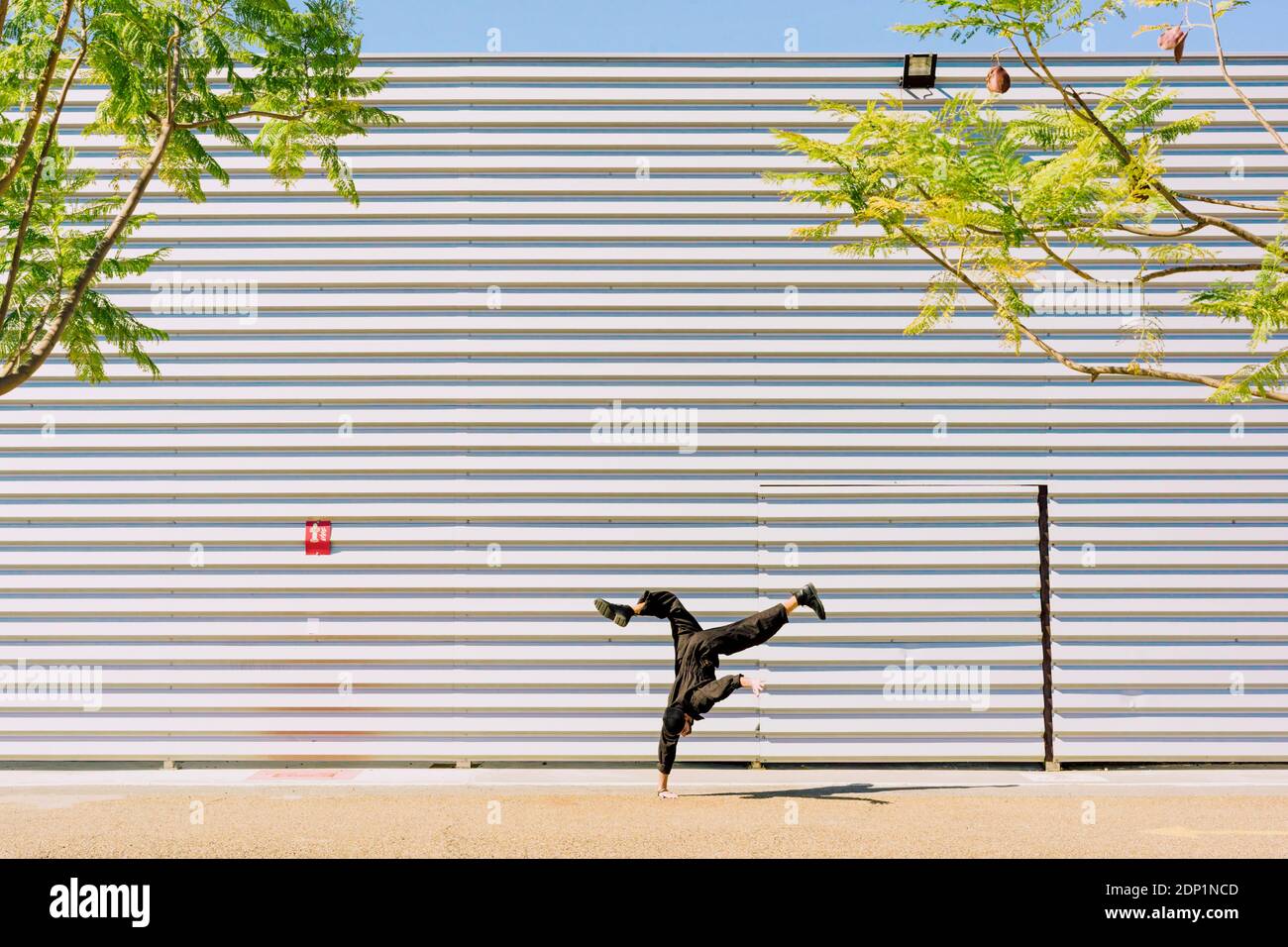 Mann trägt schwarzen Overall tun Handstand vor der Industrie Gebäude Stockfoto