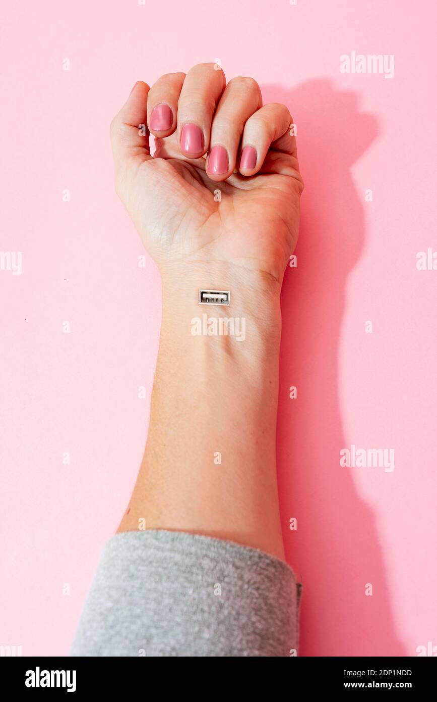 Zugeschnittenes Bild von weiblicher Hand mit Nagellack und USB Port gegen rosa Wand Stockfoto