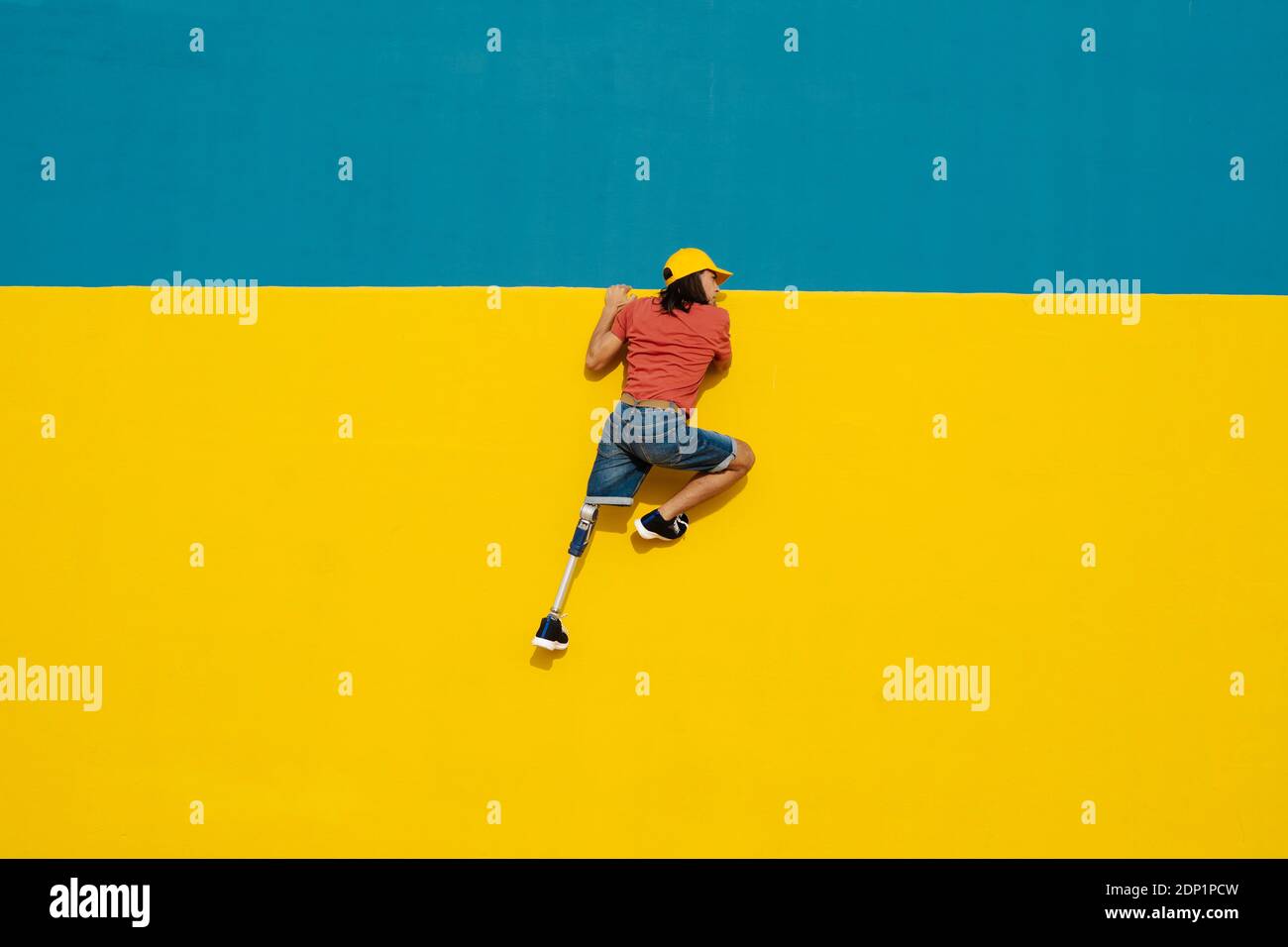 Junger Mann setzt Anstrengungen, um mehrfarbige Wand klettern Stockfoto
