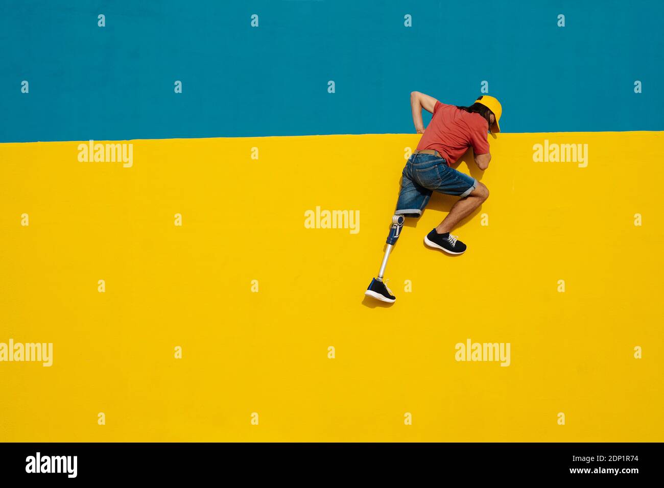 Behinderter Sportler setzt Anstrengungen, um mehrfarbige Wand klettern Stockfoto