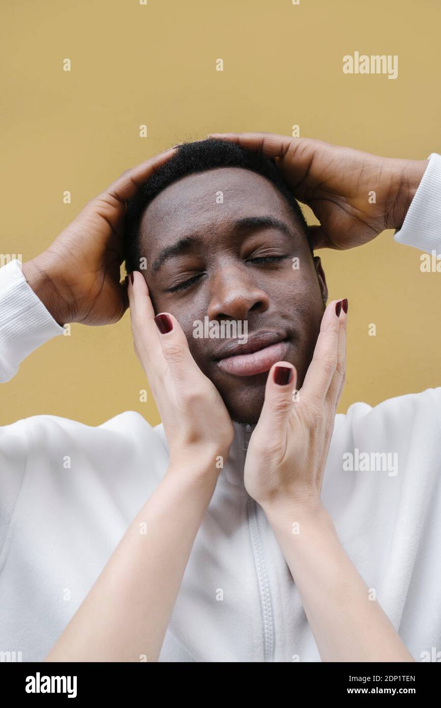 Porträt eines entspannten jungen Mannes, der von den Händen der Frau berührt wurde Stockfoto