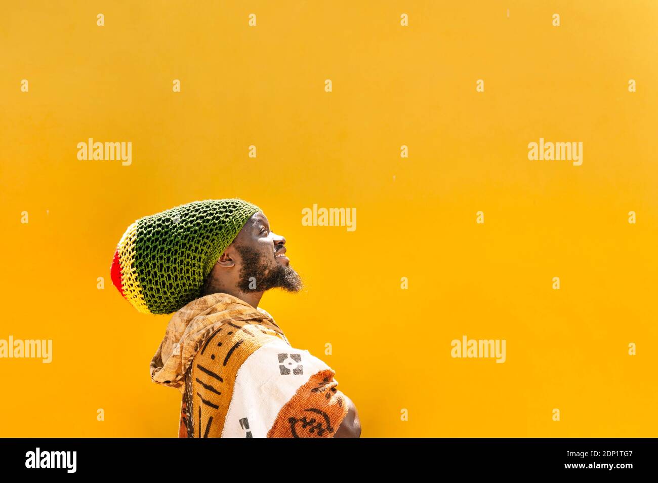 Porträt des Rastafai-Mannes mit Dreadlock-Mütze vor Yello-Hintergrund Stockfoto