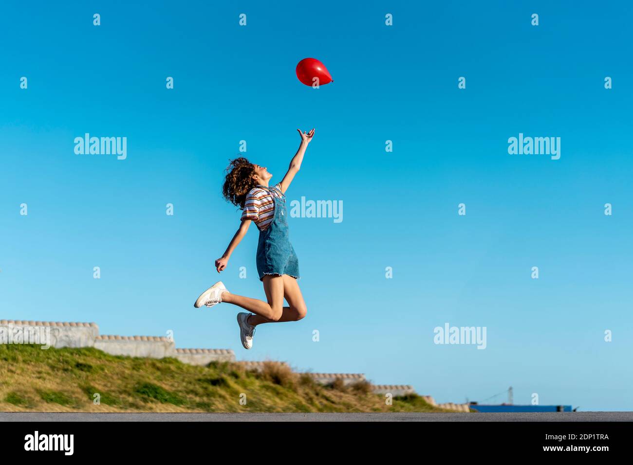 Springen junge Frau, Loslassen von einem roten Ballon Stockfoto
