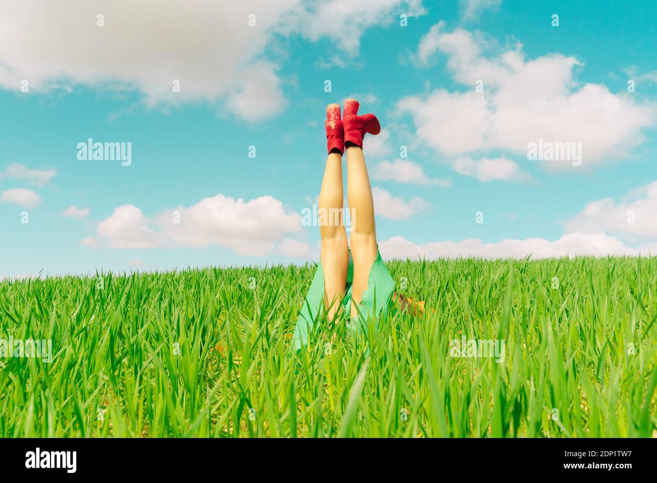Junge Frau trägt rote Schuhe auf einem Feld mit entspannen Beine in der Luft Stockfoto