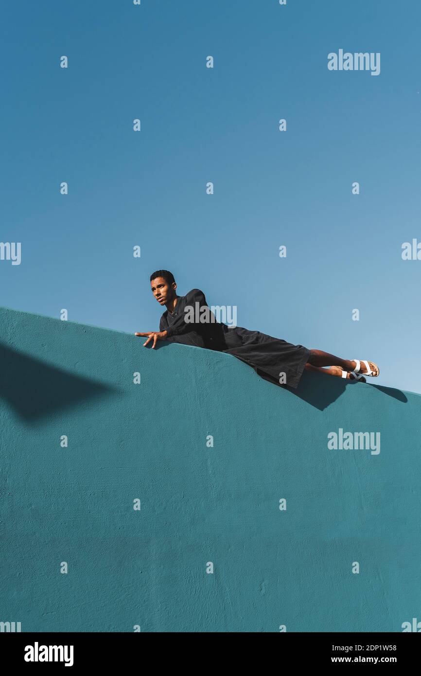 Junger Mann mit schwarzem Kaftan an blauer Wand Stockfoto