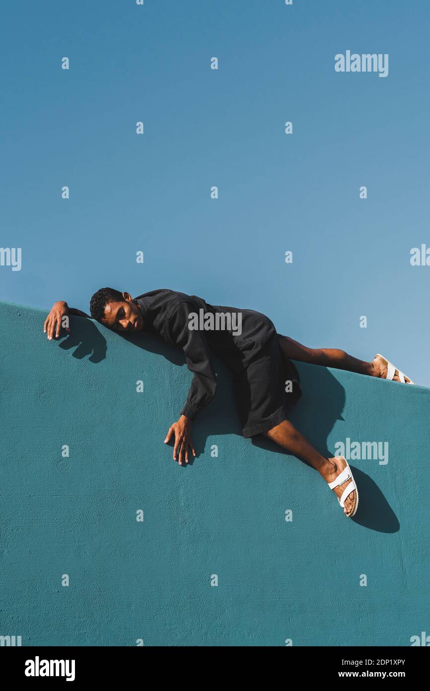 Junger Mann mit schwarzem Kaftan an blauer Wand Stockfoto