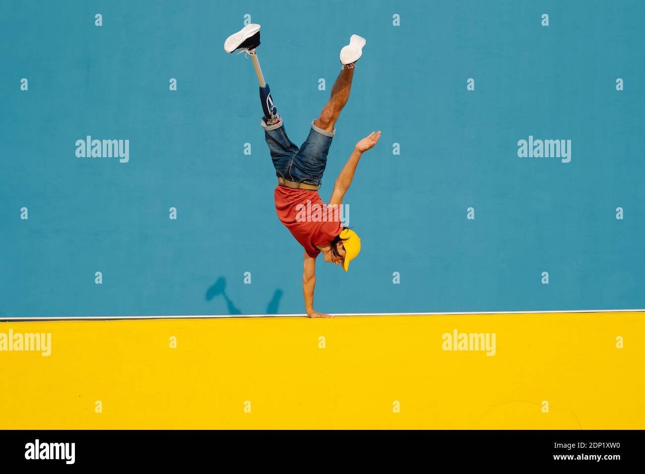 Mann, der Handstand auf vielfarbigen Wänden übt Stockfoto