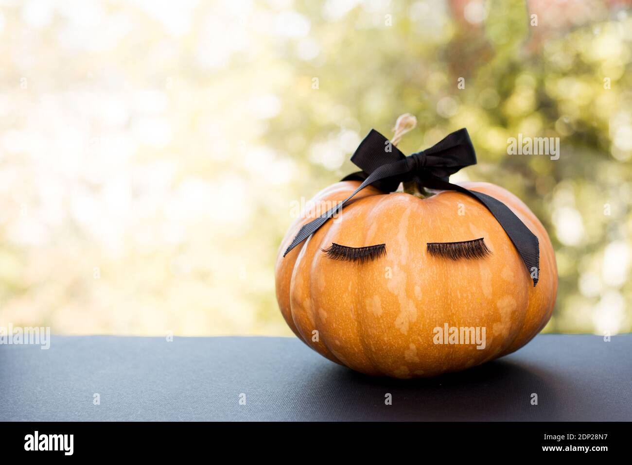 Halloween Kürbis mit Schminkwimpern und schwarzer Schleife. Konzept der Weihnachtszeit. Stockfoto