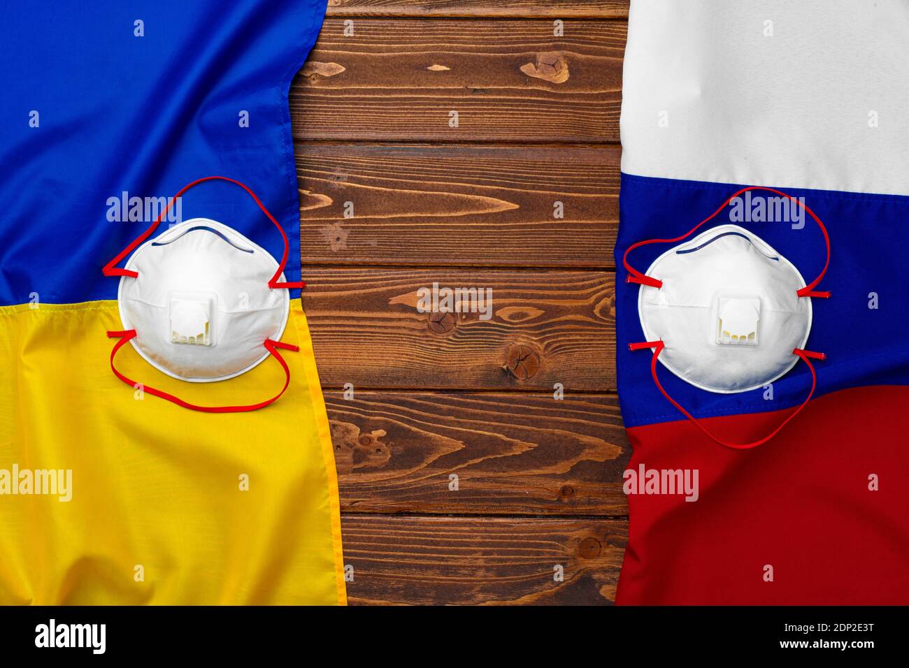 Flaggen von Russland und der Ukraine auf hölzernen Hintergrund mit medizinischen Masken Stockfoto