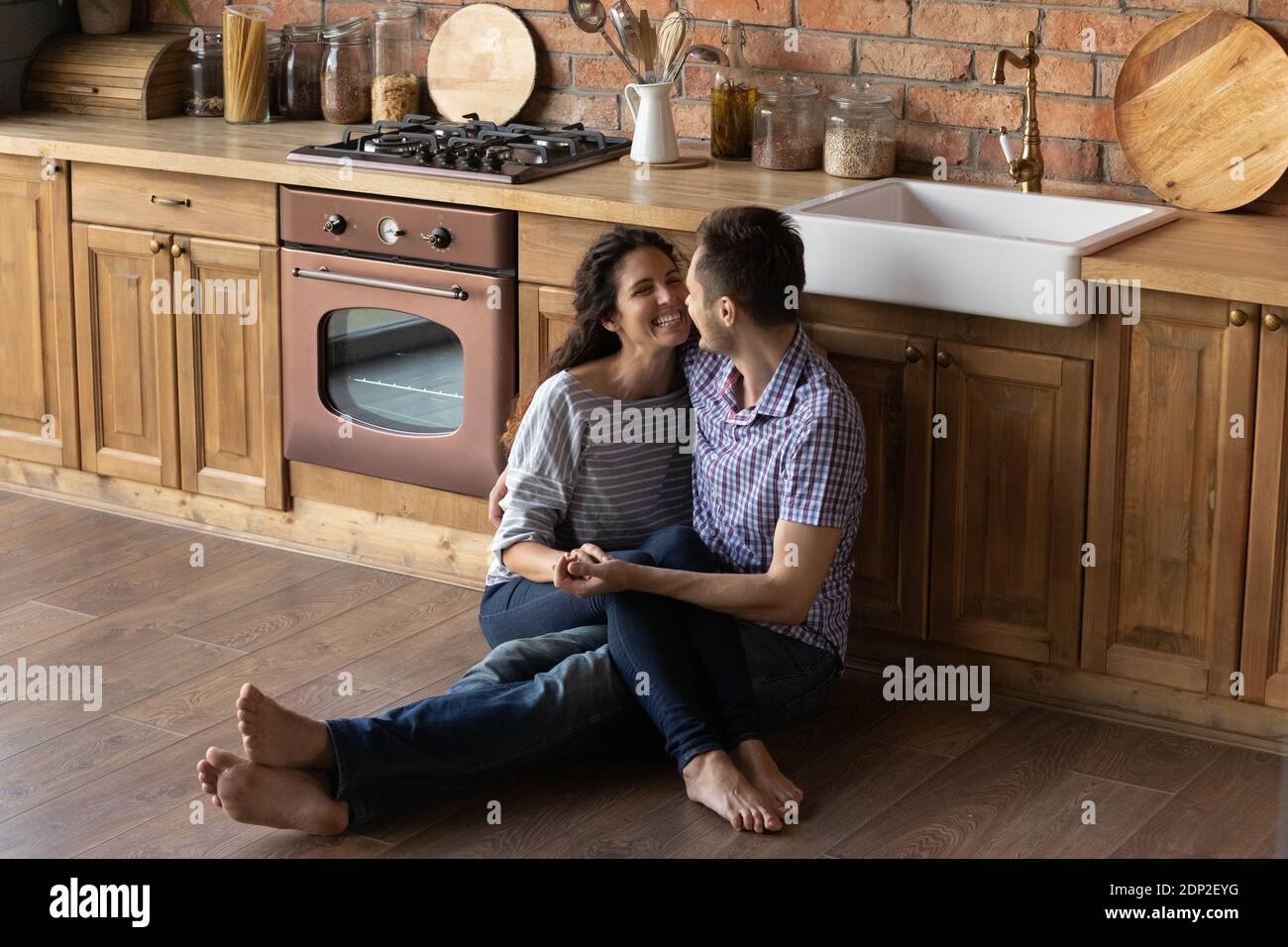 Liebevoller Ehemann sitzt auf warmem Boden und hält Frau auf Knien Stockfoto