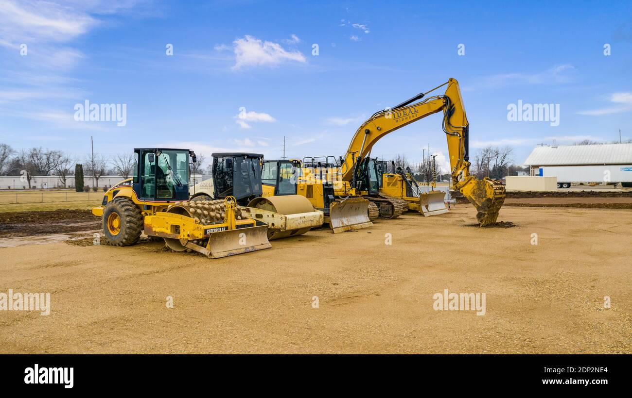 Gelbe Caterpillar-Ausrüstung auf einer Baustelle. Dazu gehören ein Baggerlader, Verdichter, Bagger und Planierraupen. Stockfoto