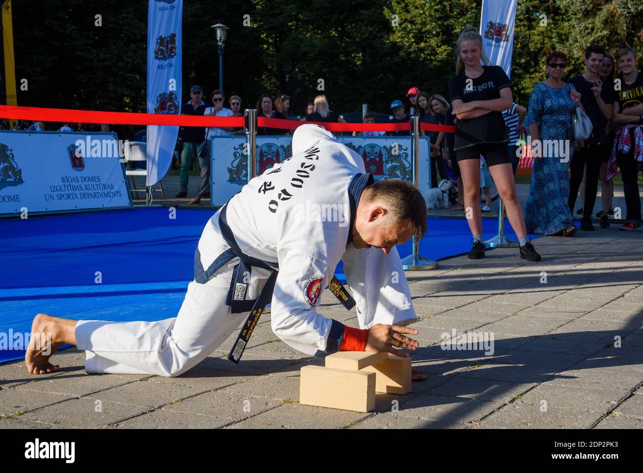 RIGA, LETTLAND. August 2019. Tang Soo macht die Meisterleistung der Kampfkunst. Ziegel brechen. Stockfoto