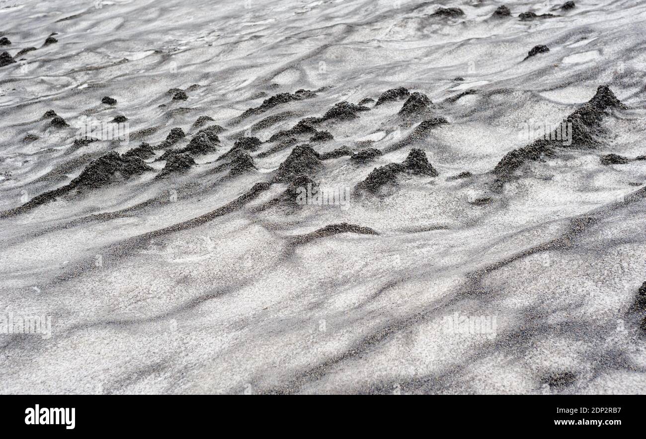Abstrakt schmutzige schwarze Sandwellen auf Schneetextur. Stockfoto