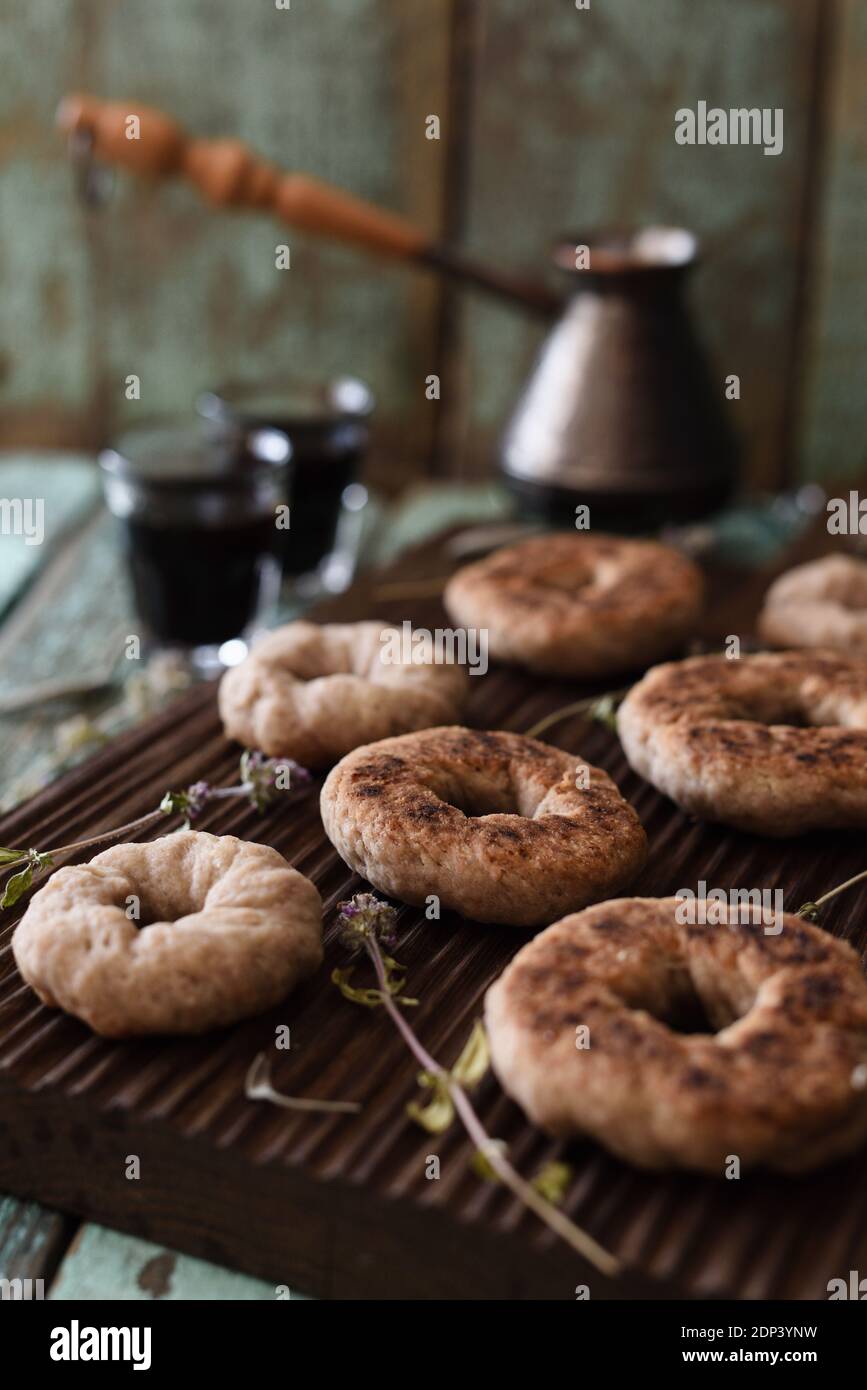 Kaffeestzeit. Hausgemachte Vollkornplätzchen und Kaffee in türkischen Cezve auf Eichenbrett auf schäbigen blauen Hintergrund vertikal gebrüht Stockfoto