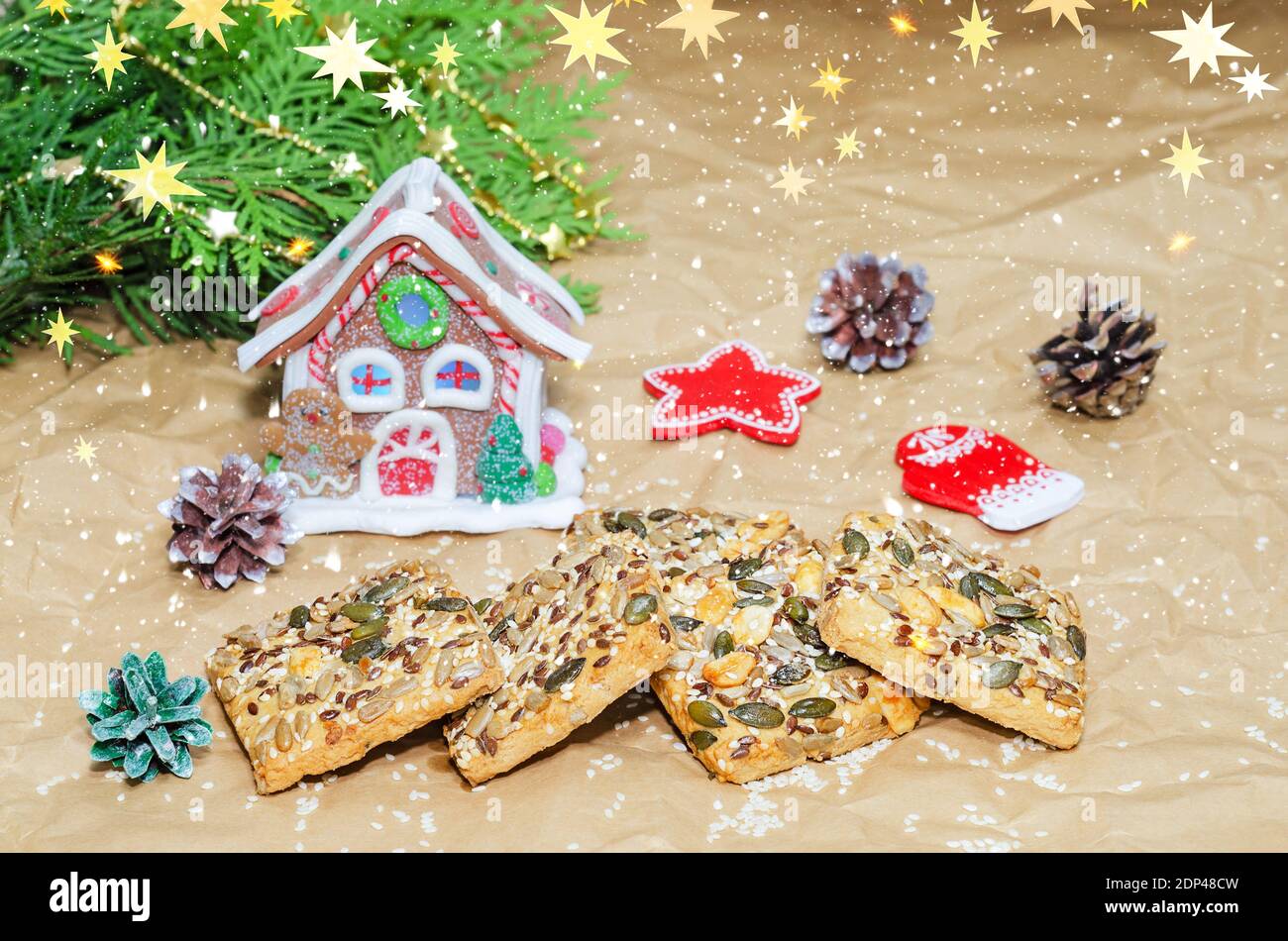 Shortbread-Kekse mit verschiedenen Samen und Weihnachtsschmuck auf zerknittertem Papier. Überlagern von Schnee und Sternen Stockfoto