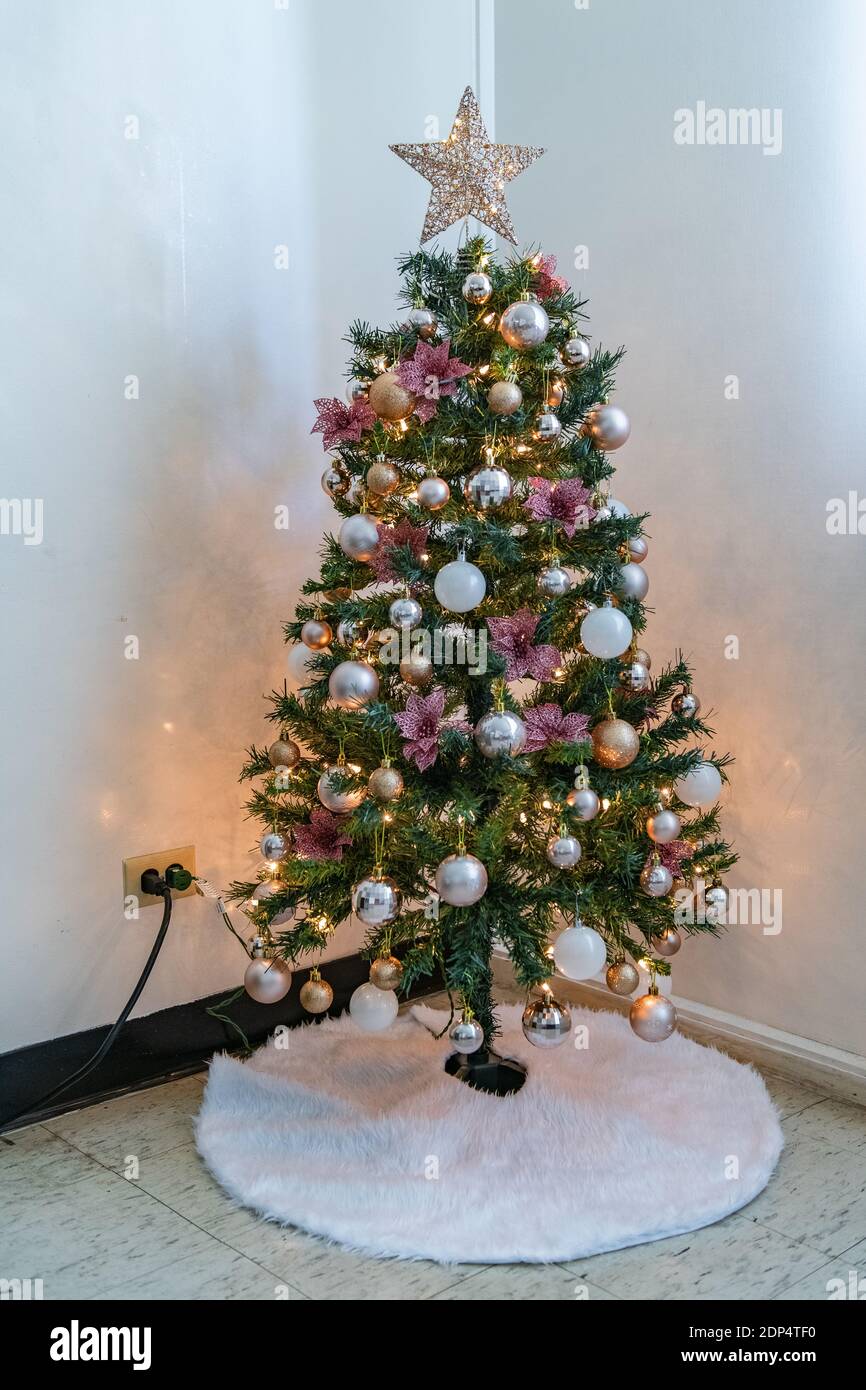 Kleiner Weihnachtsbaum mit rosa, Gold und weißen Ornamenten im Inneren des kleinen Wohnraumes. Stockfoto