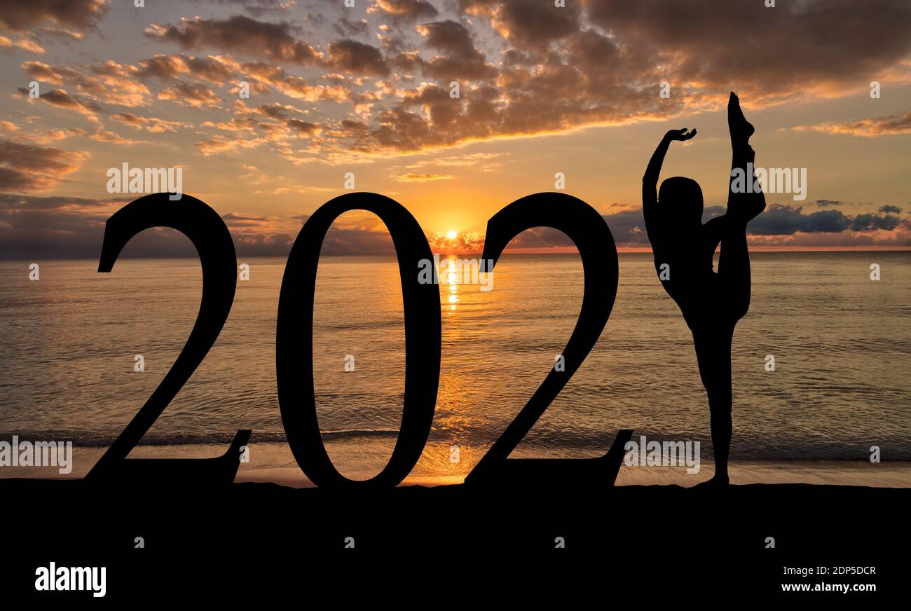 Neujahr 2021 Sonnenaufgang am Strand mit Silhouette der Frau in Tanzpose. Stockfoto