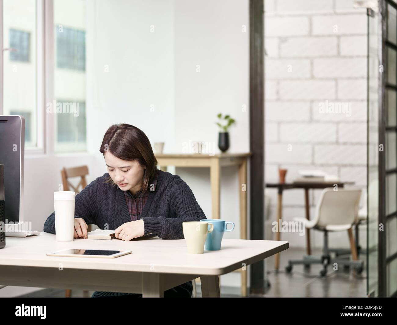 Junge asiatische Geschäftsfrau liest ein Buch Stockfoto