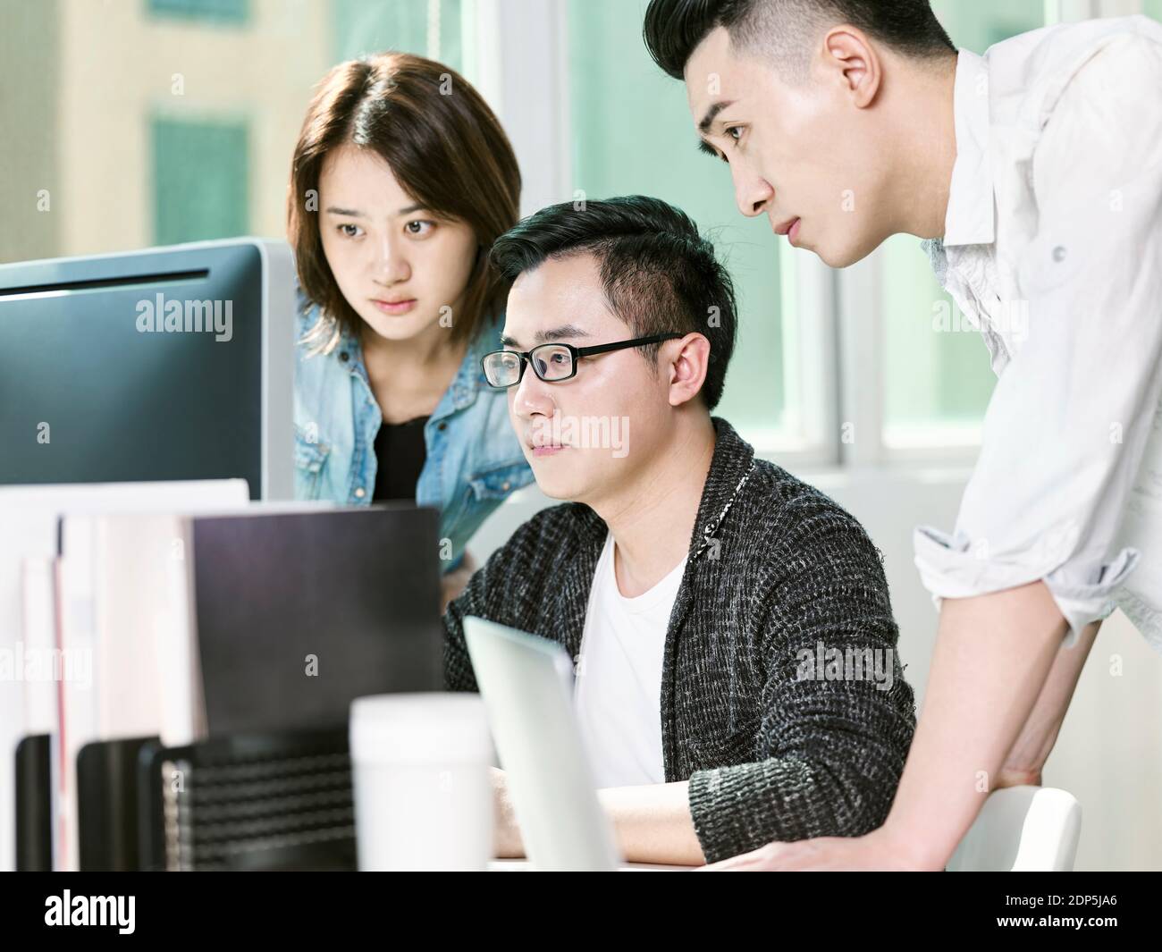 Team von drei Jungunternehmern, die Daten im Büro analysieren mit Desktop-Computer Stockfoto