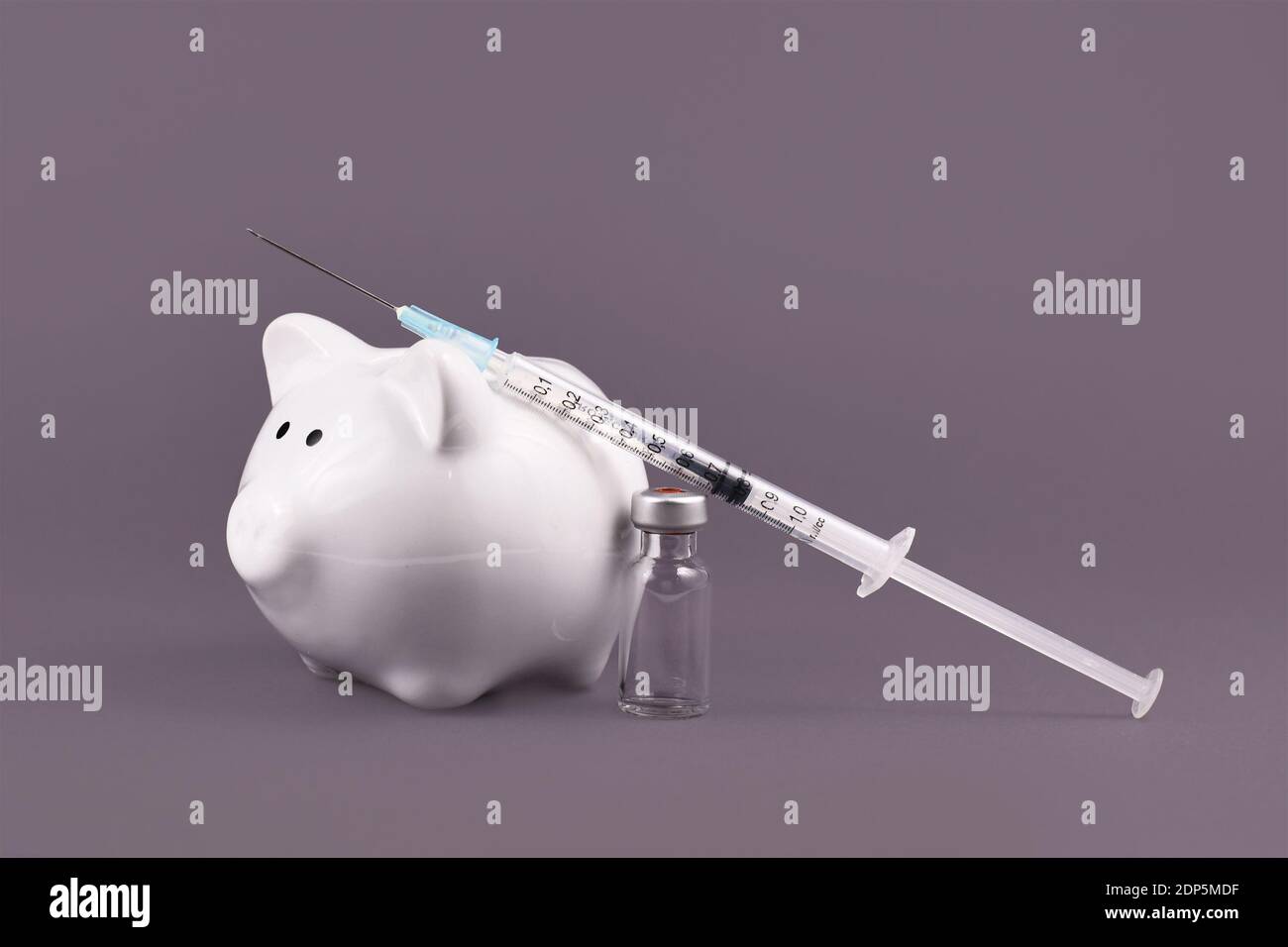 Corona-Virus-Impfkostenkonzept mit Spritze, Impffläschchen und Sparschwein auf grauem Hintergrund Stockfoto