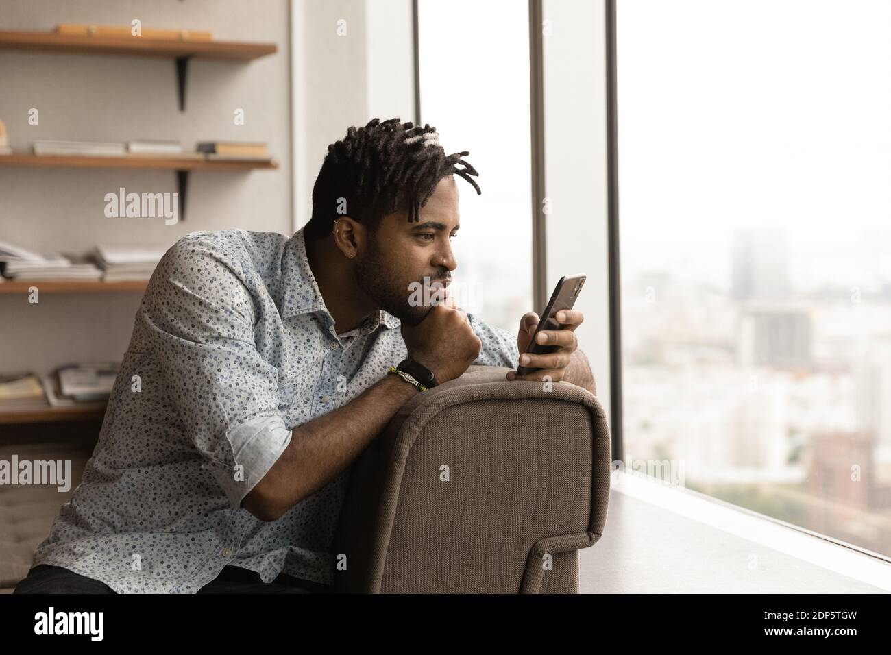 Afroamerikanischer Mann benutzt Handy zu Hause Stockfoto