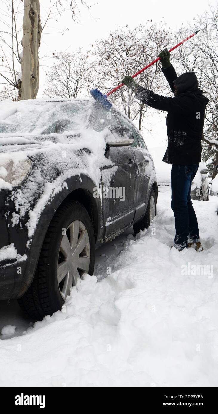 Ein Mann reinigt ein Auto von Schnee mit einem Besen Stockfotografie - Alamy
