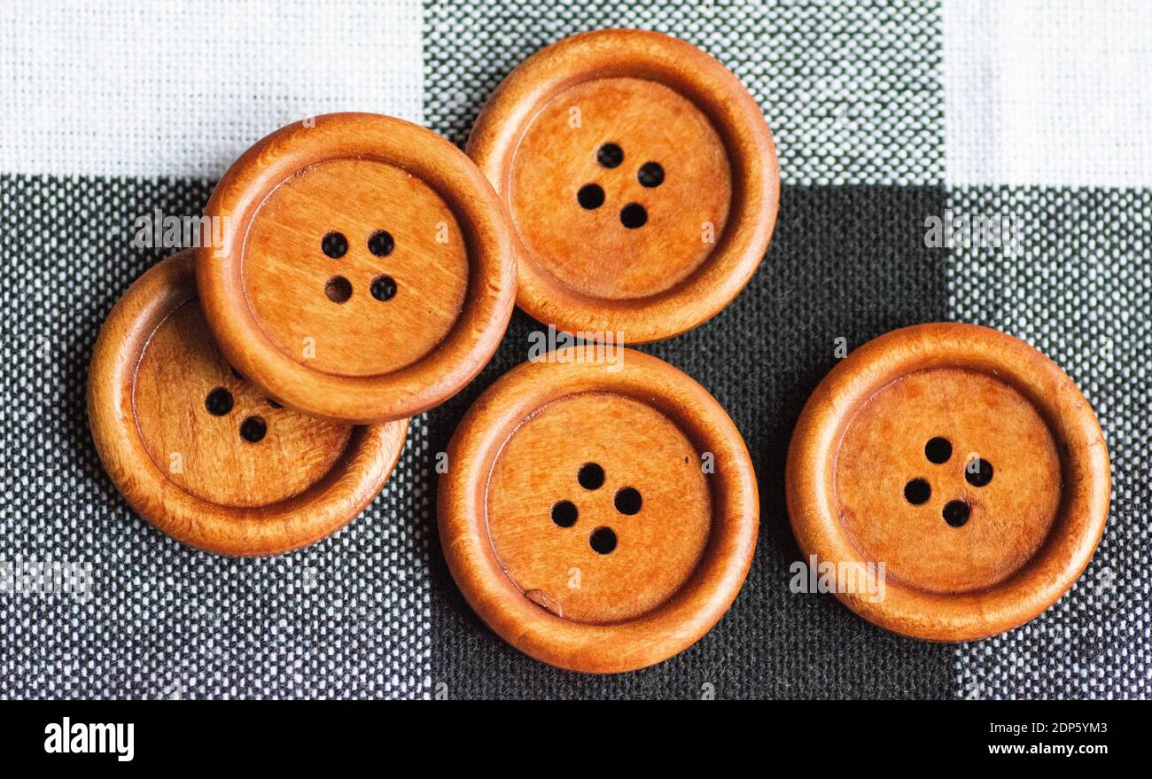 Runde braune Nähknöpfe aus Holz isoliert auf textilen Hintergrund. Draufsicht . Nahaufnahme. Makro. Stockfoto