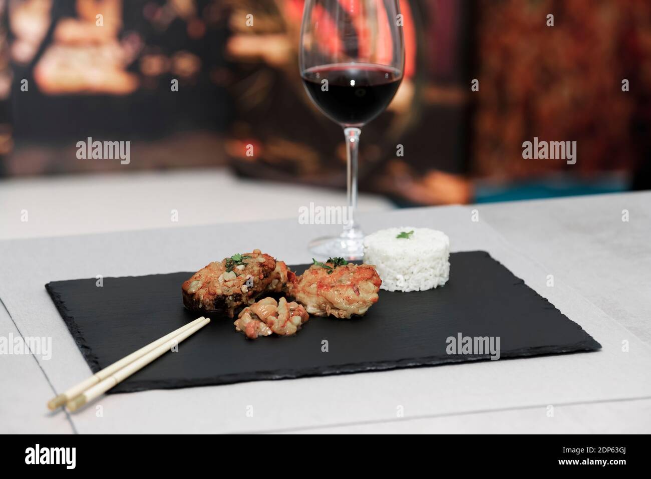 Gebratenes Hähnchen mit gehackter Kastaniensoße und Reistimbale auf einem dunklen Tablett auf einem Hintergrund. Selektiver Fokus Stockfoto