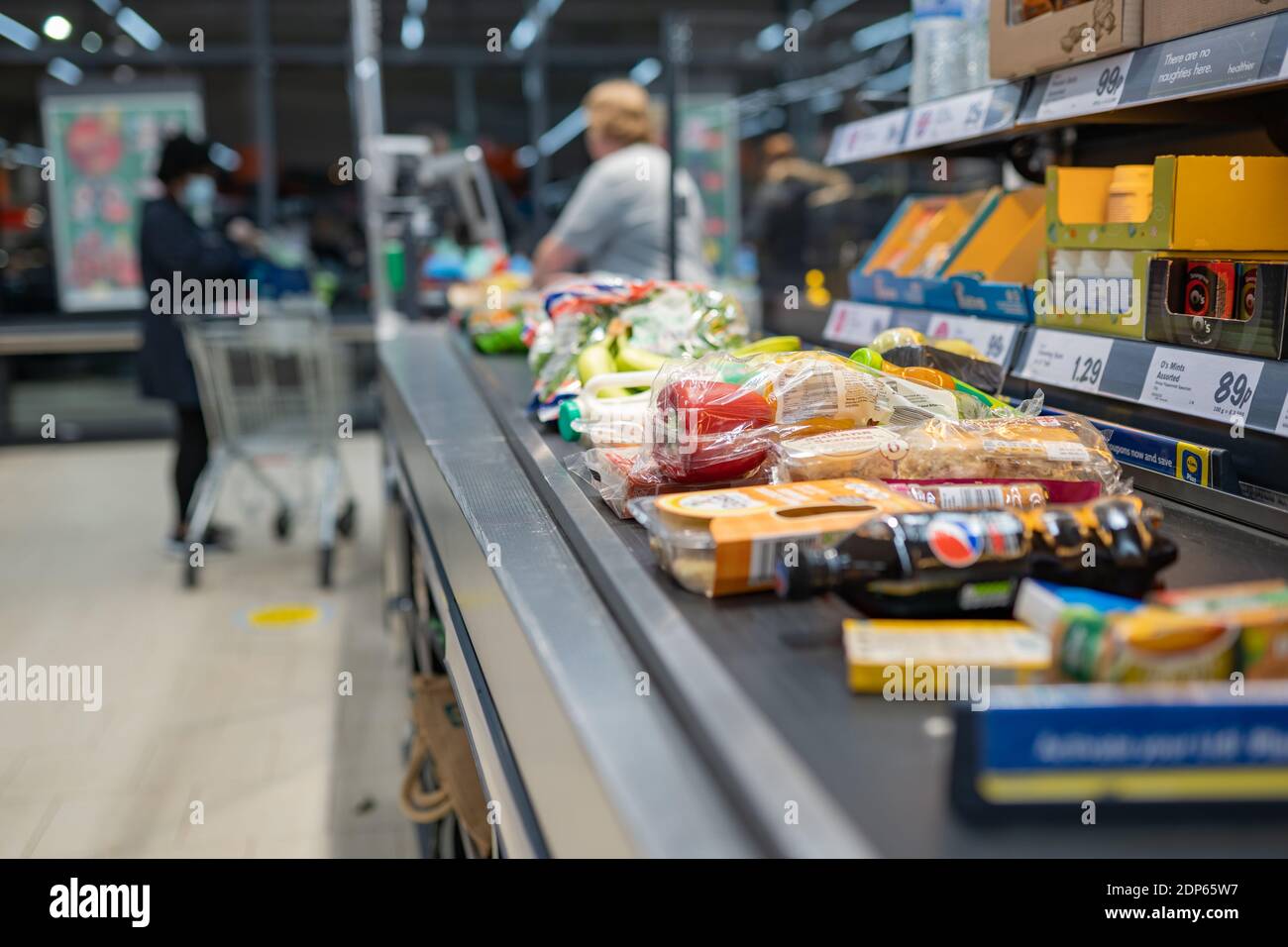 Lebensmitteleinkäufe bei Lidl in Großbritannien, Kasse Kassierer Counter Gürtel voller Lebensmittel im Supermarkt. Einkaufen mit sozialen Distanzierungsmaßnahmen in Geschäften Stockfoto