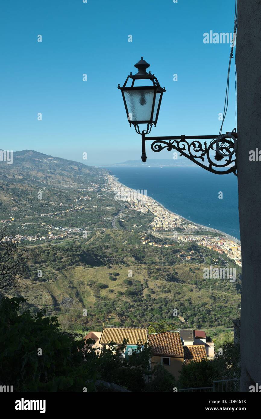 Hoher Aussichtspunkt an der dicht besiedelten Ostküste Siziliens am Meer, im Vordergrund Silhouette einer Laterne alten Stil Stockfoto