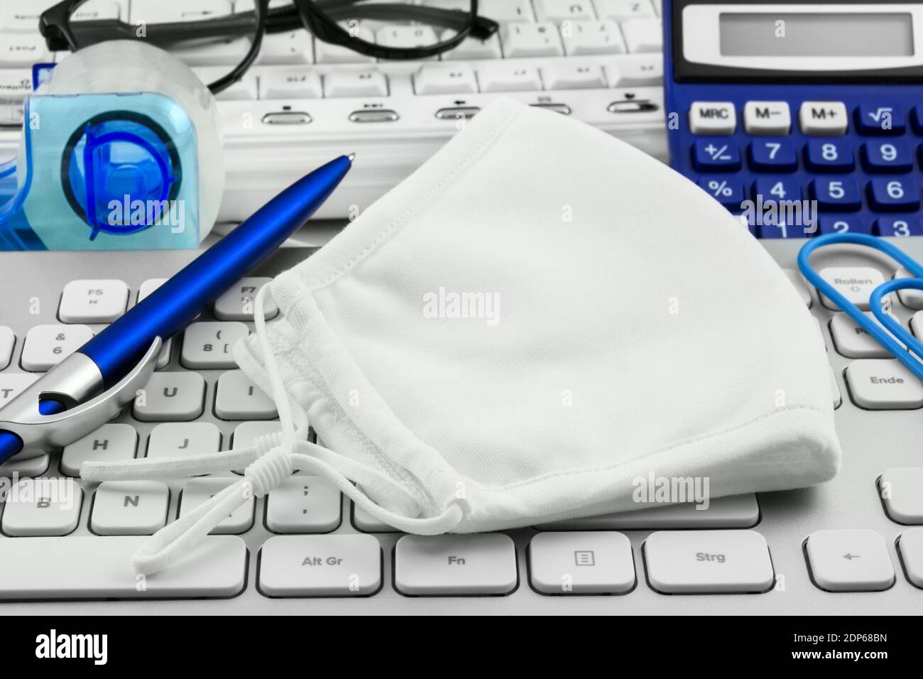 Tragen Sie eine Maske und ein Büro mit pc-Tastatur Stockfoto