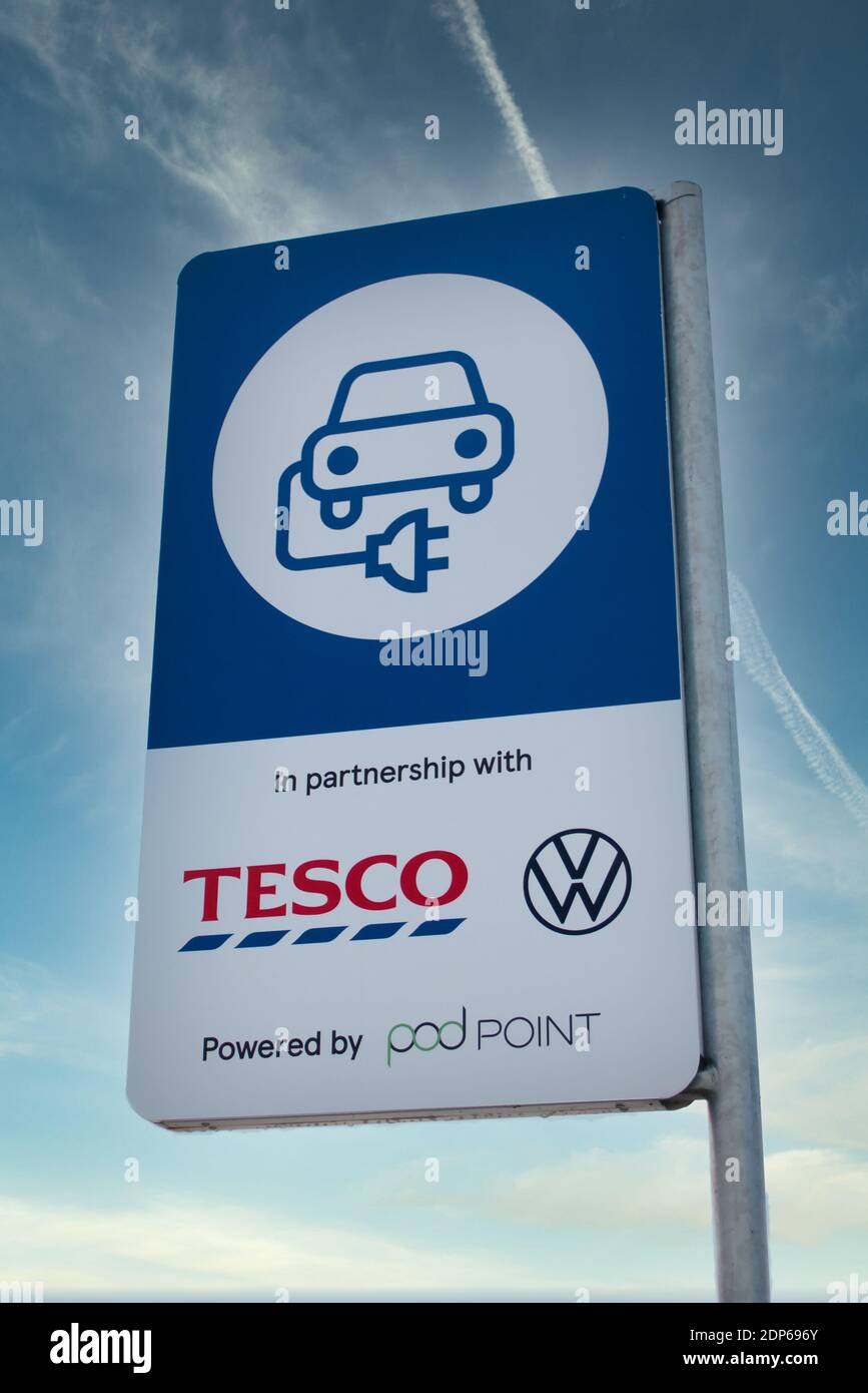 Wirral, UK Dez 12 2020: Ein Schild in einem Tesco Supermarkt Kundenparkplatz, der Elektrofahrzeuge über das Pod Point Netz anwirbt Stockfoto