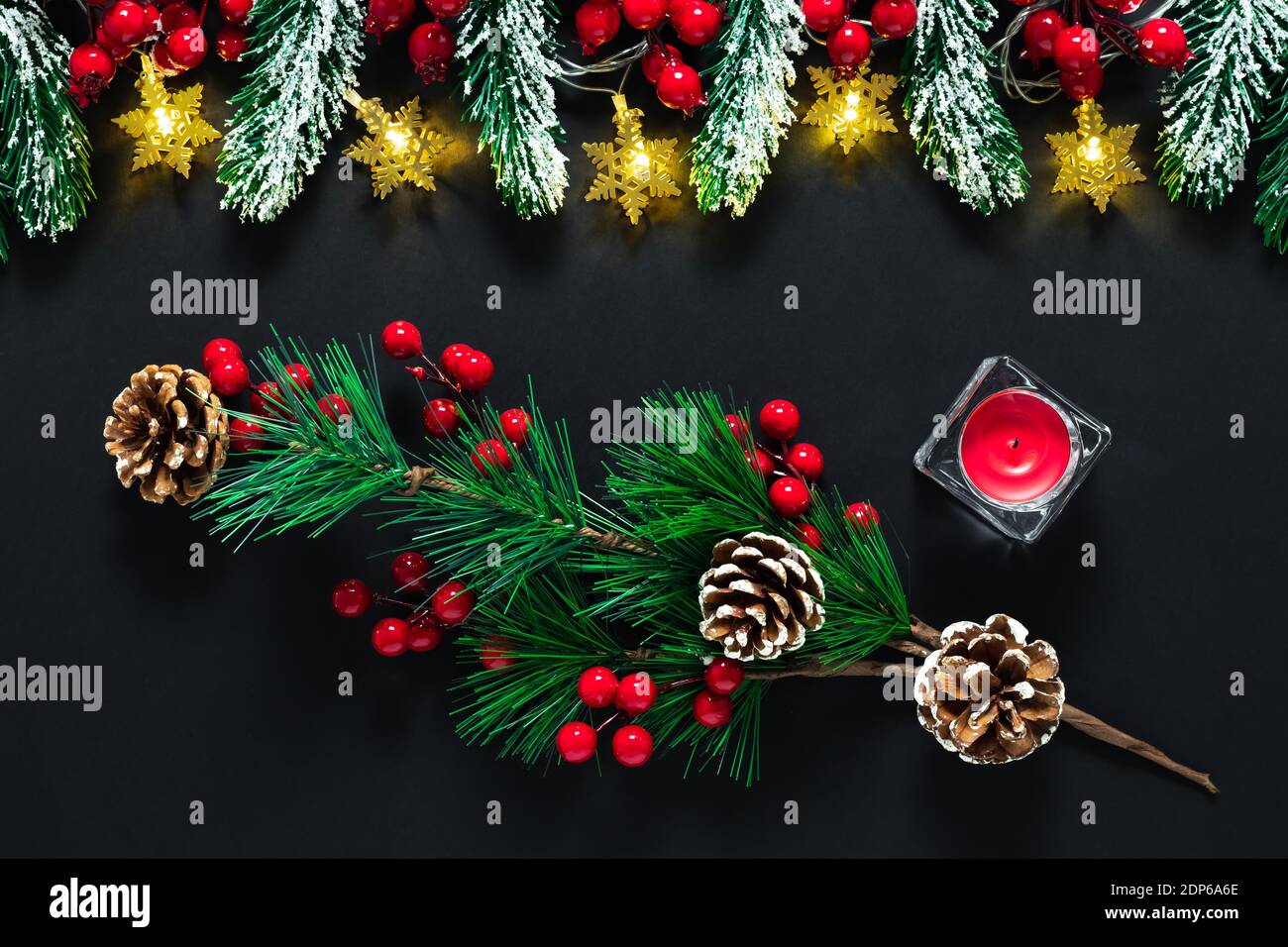 Schwarze Weihnachtskarte, Neujahrshintergrund mit grünen Tannenzweigen, Tannenzapfen, roten Beeren und Kerze. Winterurlaub Konzept, Ornament pa Stockfoto