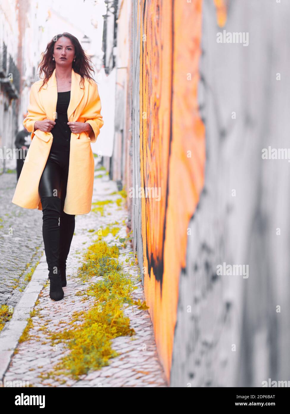 Schöne große Frau trägt lange gelbe Mantel ein Gehen in Richtung Kamera Stockfoto