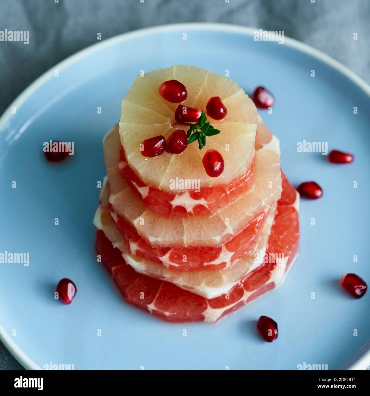 Stapel von geschnittenen runden Scheiben roter und weißer Grapefruit Mit Granatapfel bestreut Stockfoto