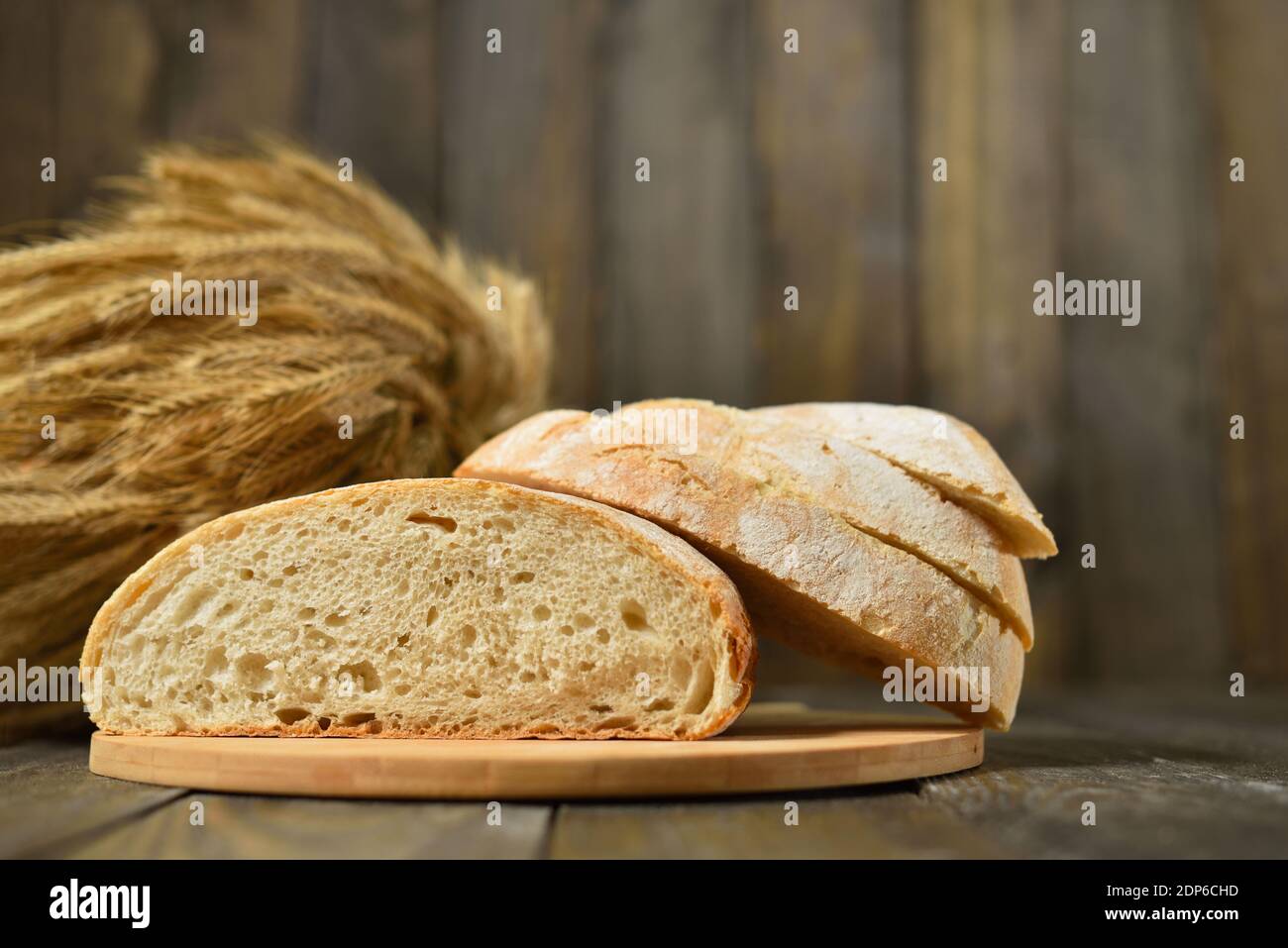 Frisches Brot in Scheiben auf einem Holzwandhintergrund Stockfoto