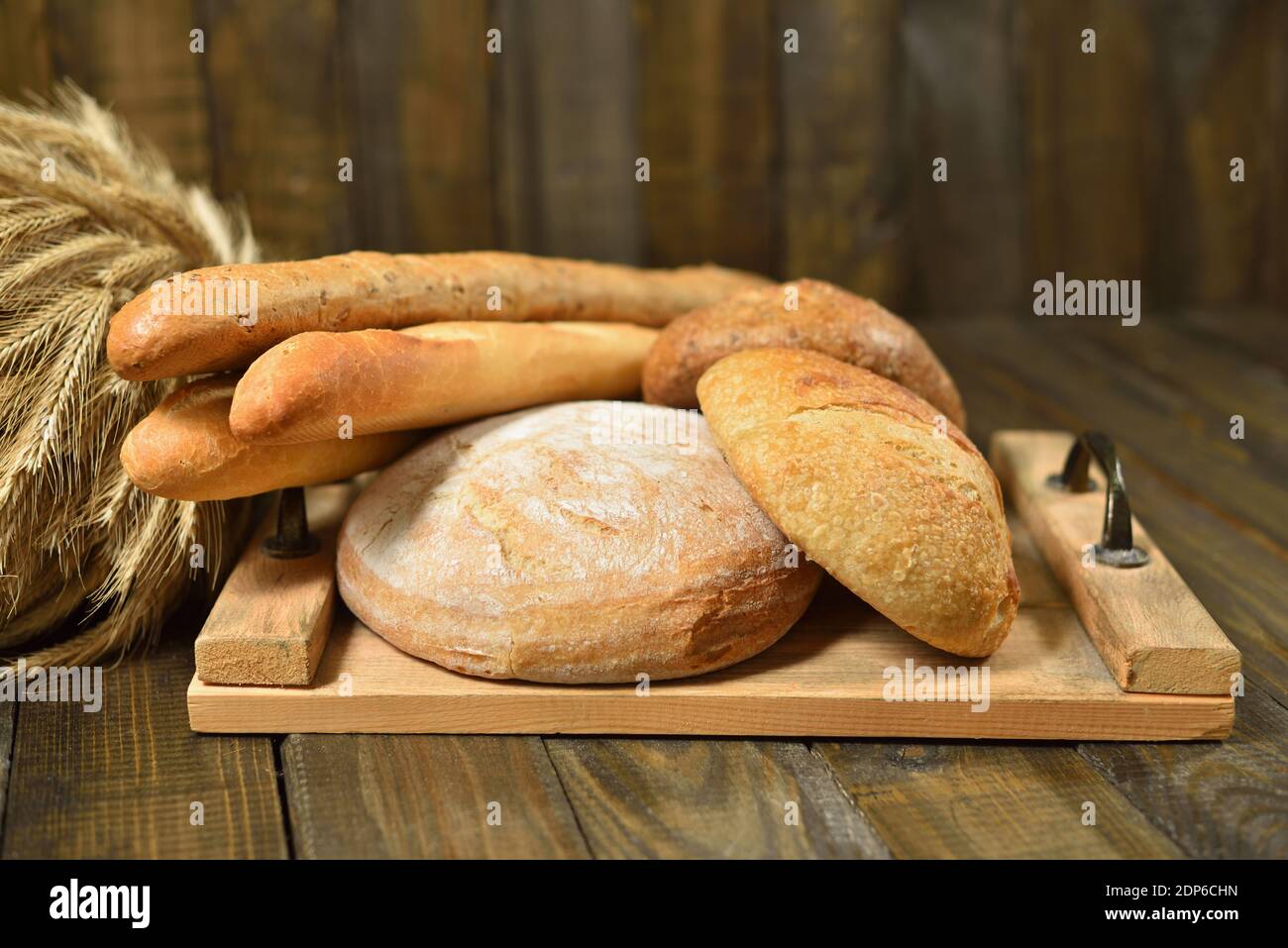 Verschiedene Brote auf Schneidebrett auf einem Holzhintergrund Stockfoto