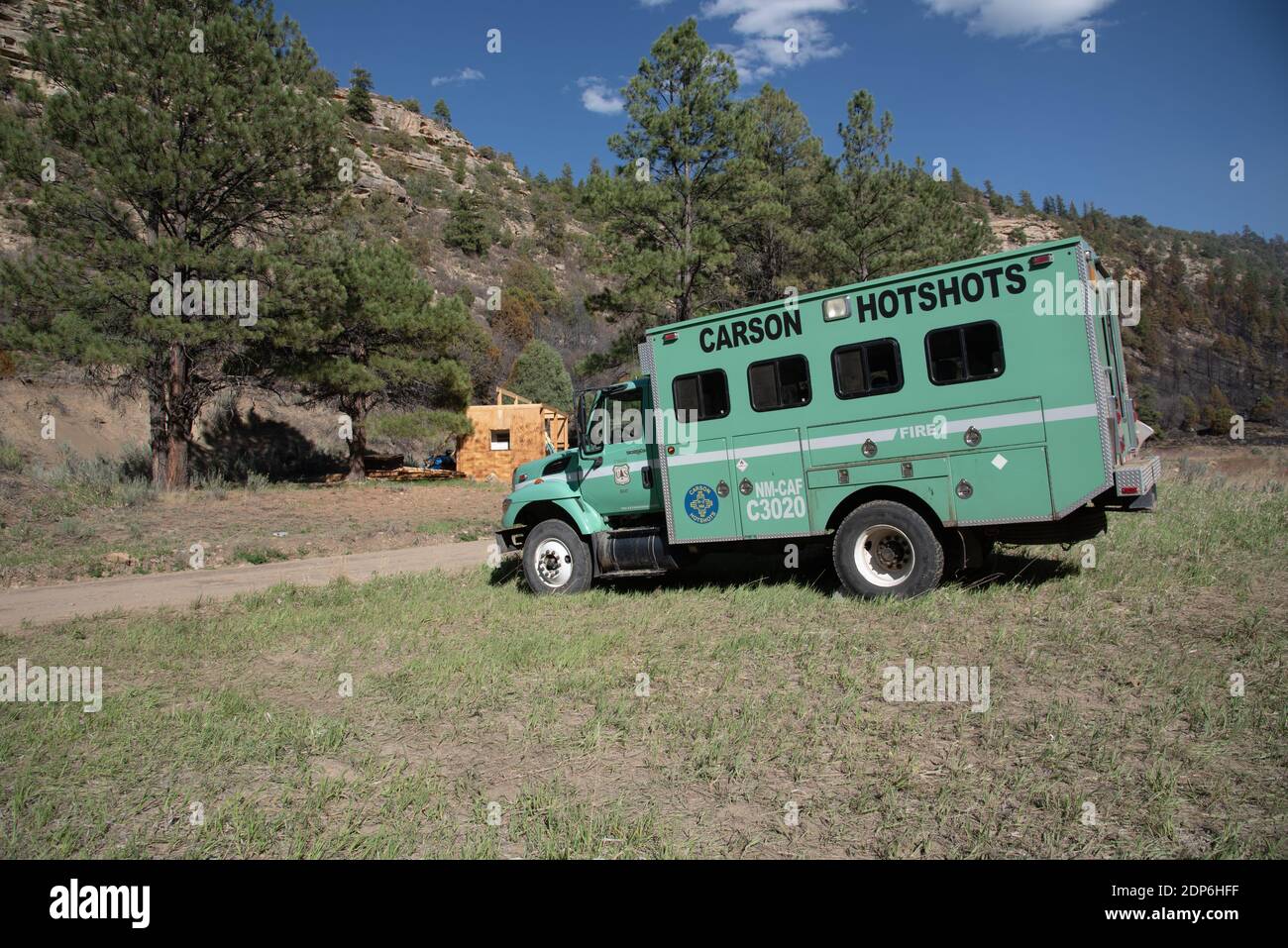 Im spärlichen Gras an einer unbefestigten Straße in New Mexico wird ein Feuerwehrauto geparkt. Stockfoto