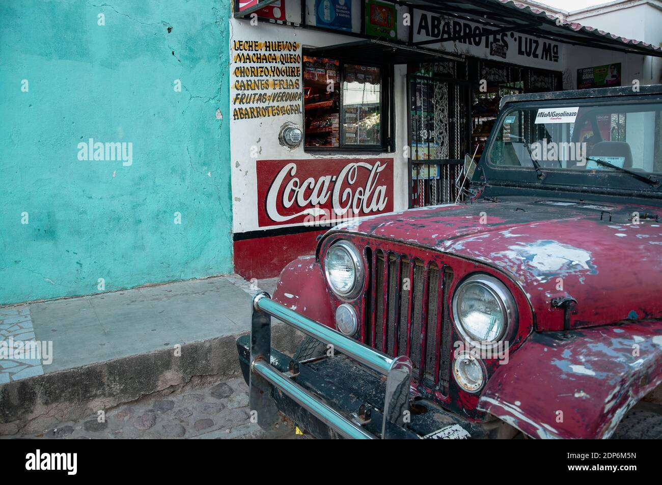 Ein rotes Offroad-Auto mit abgeplatzter Farbe parkt vor einem kleinen Laden in Mexiko. Stockfoto