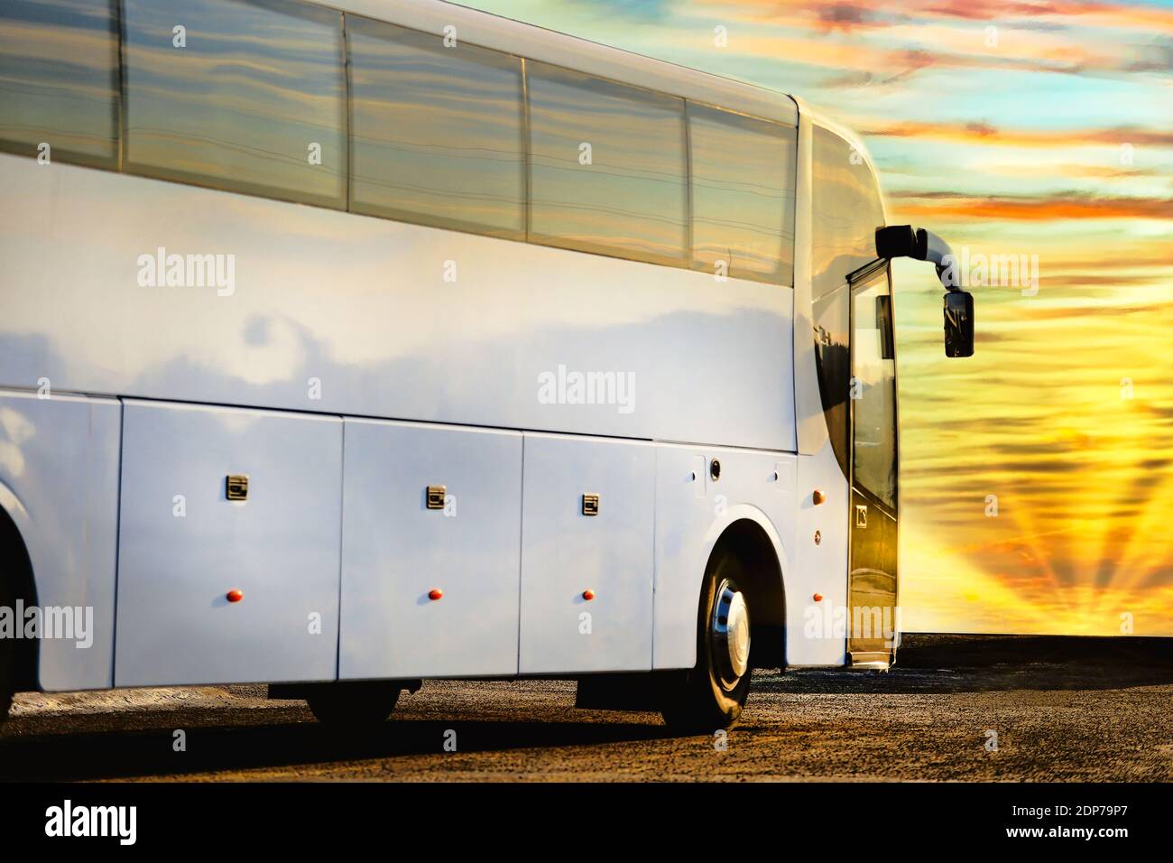 Nahaufnahme eines weißen Reisebusses mit Blick auf den wunderschönen Morgenhimmel mit aufgehender Sonne. Stockfoto