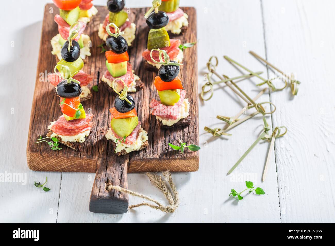 Verschiedene kalte Snacks aus Gemüse, Fleisch und Kräutern auf weißem Tisch Stockfoto
