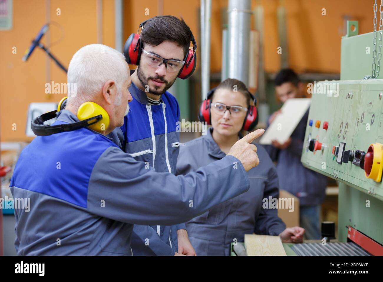 Leitender Ingenieur, der Maschinen für männliche und weibliche Auszubildende ausgibt Stockfoto